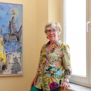 Gerda Laufenberg lehnt neben einem Kölnbild an einer Fensterbank.