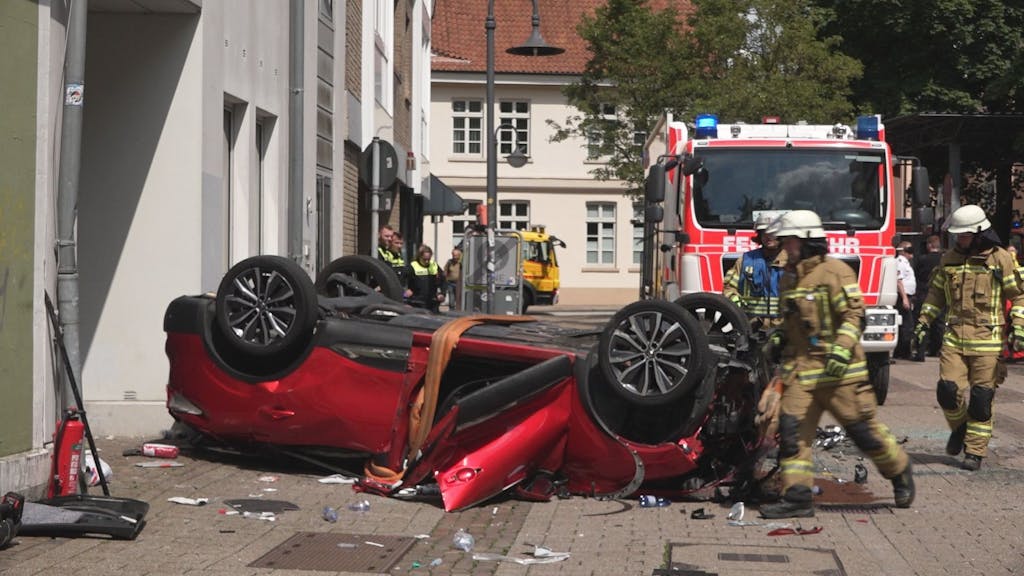 Vor einem Parkhaus in Oldenburg liegt am 30. Juni 2023 ein Auto auf dem Dach. Der Wagen war aus dem vierten Stock des Parkhauses auf die Straße gefallen.