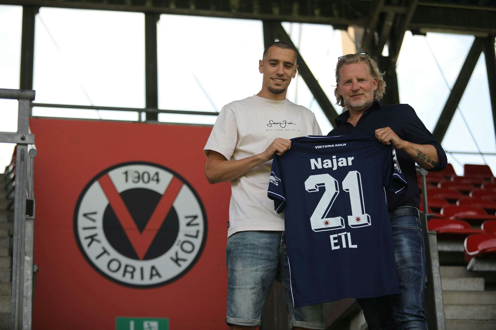 Suheyel Najar und Stephan Küsters posieren mit Najars Trikot mit der Rückennummer 21.