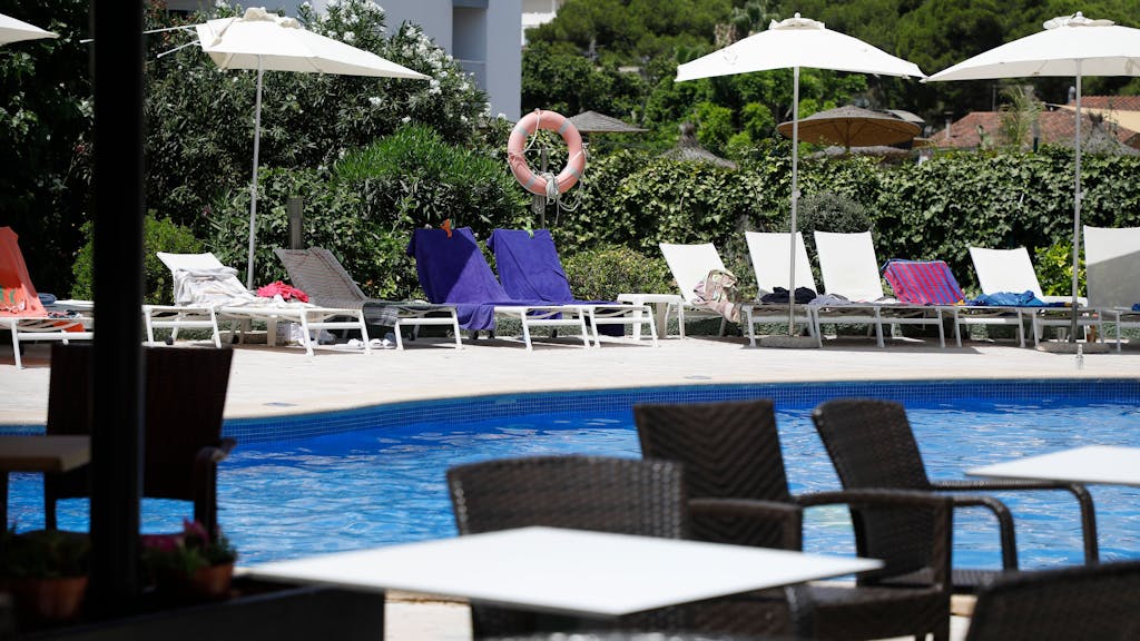 Handtücher liegen auf Sonnenliegen an einem Hotel-Pool auf Mallorca.