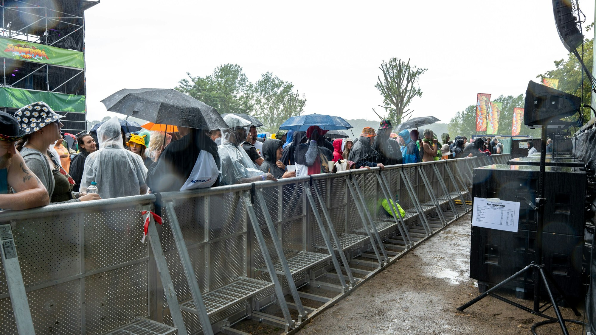 Mit Regenschirm vor der Bühne: Besucherinnen und Besucher beim Summerjam-Festival schauen trotz Regen Konzert.