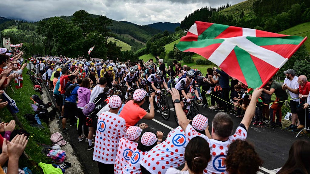 Fans bejubeln die Fahrer der Tour de France am Straßenrand.