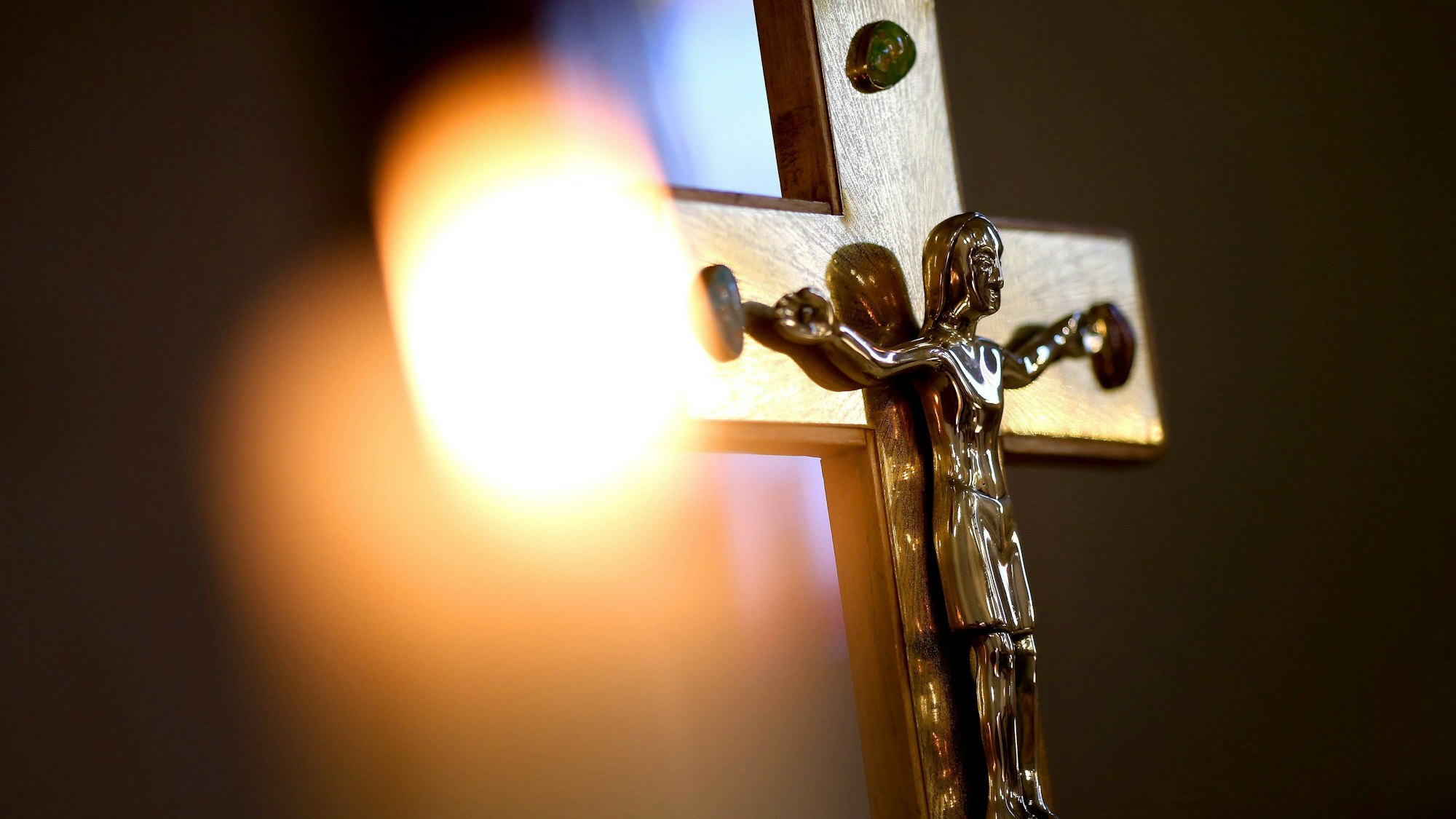 Ein Jesuskreuz und eine brennende Kerze in einer Kirche.