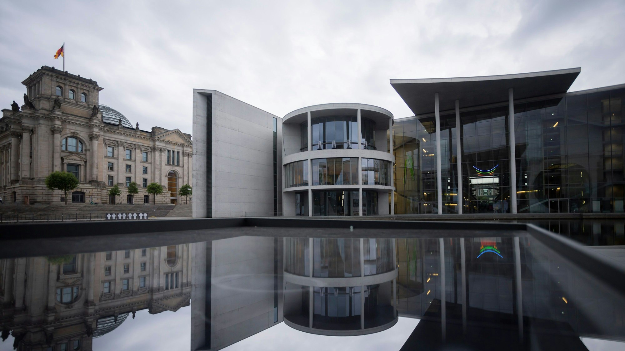 Das Paul-Löbe-Haus (M) des Deutschen Bundestages spiegelt sich neben dem Reichstagsgebäude (l) in einer Glasfläche.