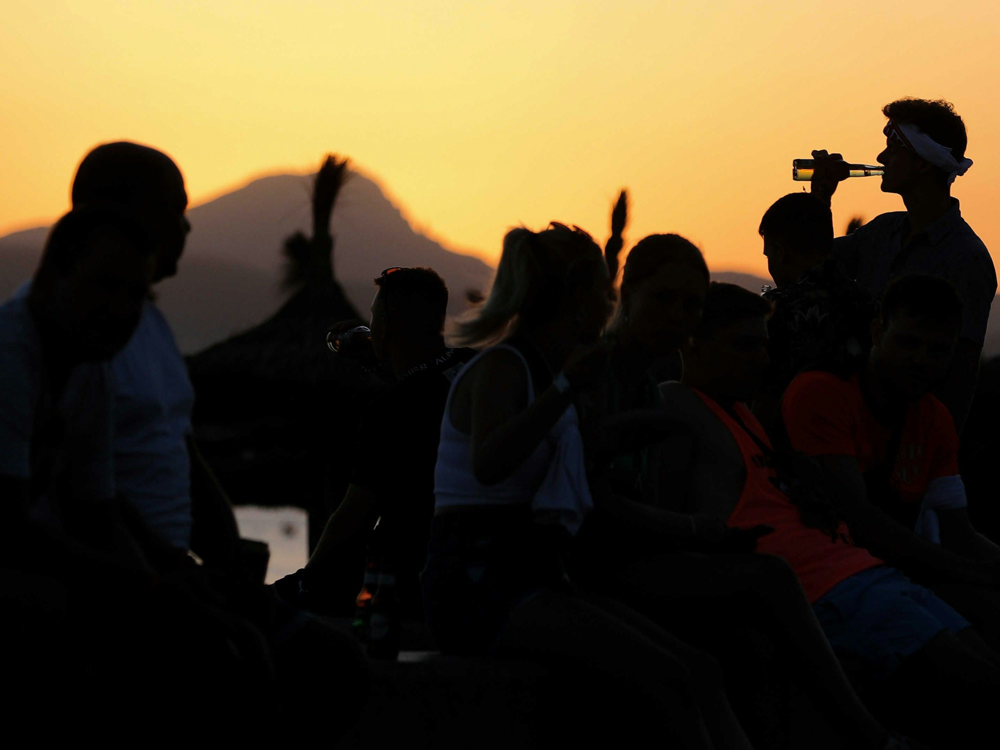 Vorwiegend junge Leute feiern bei Sonnenuntergang am Strand von Arenal am Party-Viertel Ballermann auf Mallorca.