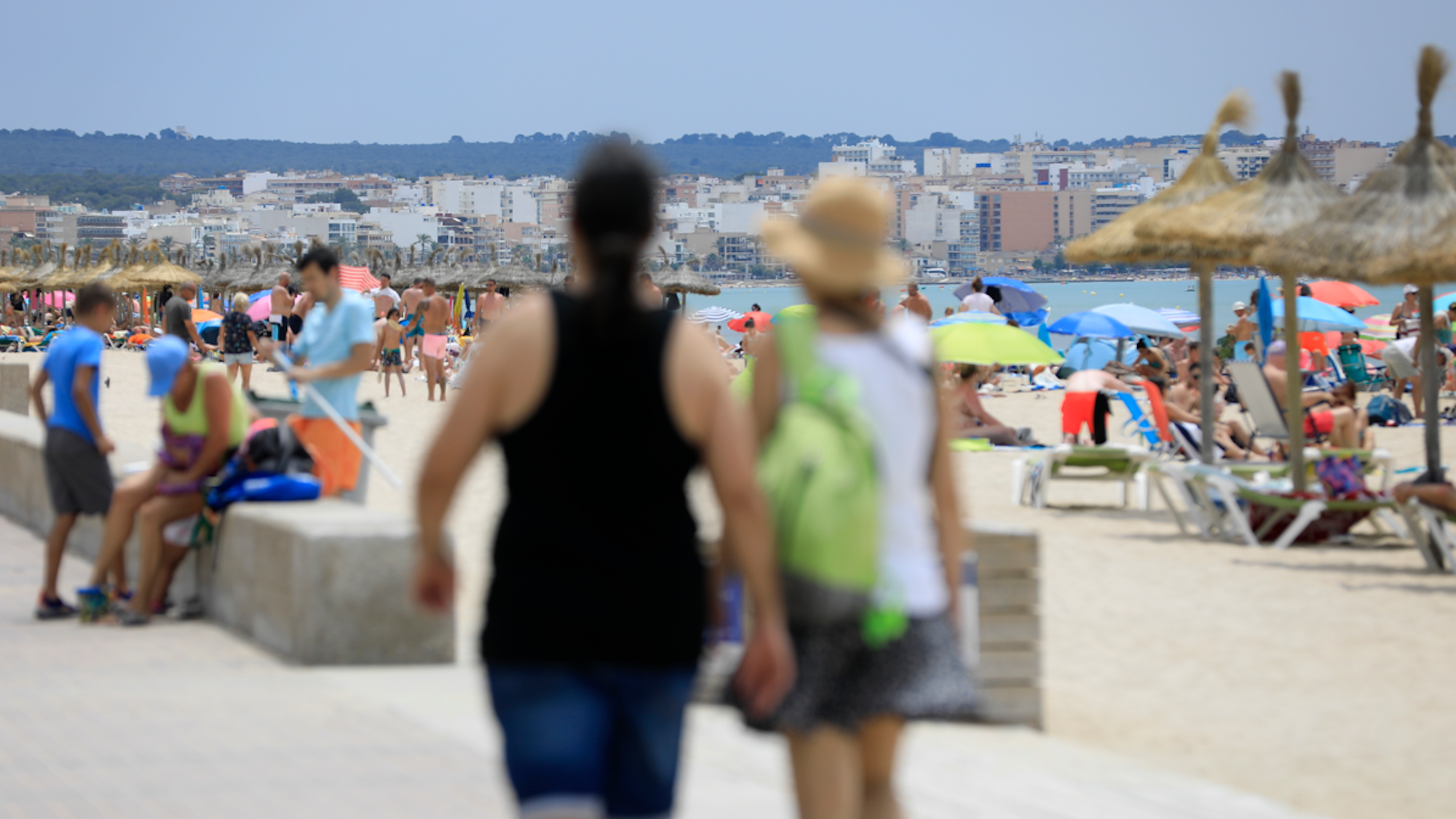 Menschen genießen die sommerlichen Temperaturen am Strand von dem Badeort S`Arenal auf der Baleareninsel Mallorca.