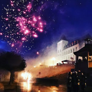 Ein Feuerwerk am Nachthimmel vor der Kulisse des Porzer Rathauses.&nbsp;