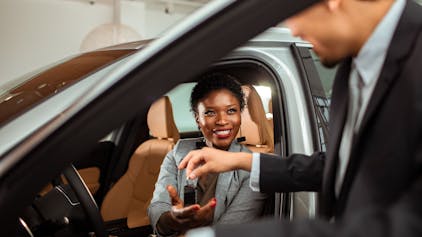 Close up of a mature woman talking to the car salesman about a car purchase while checking out the car