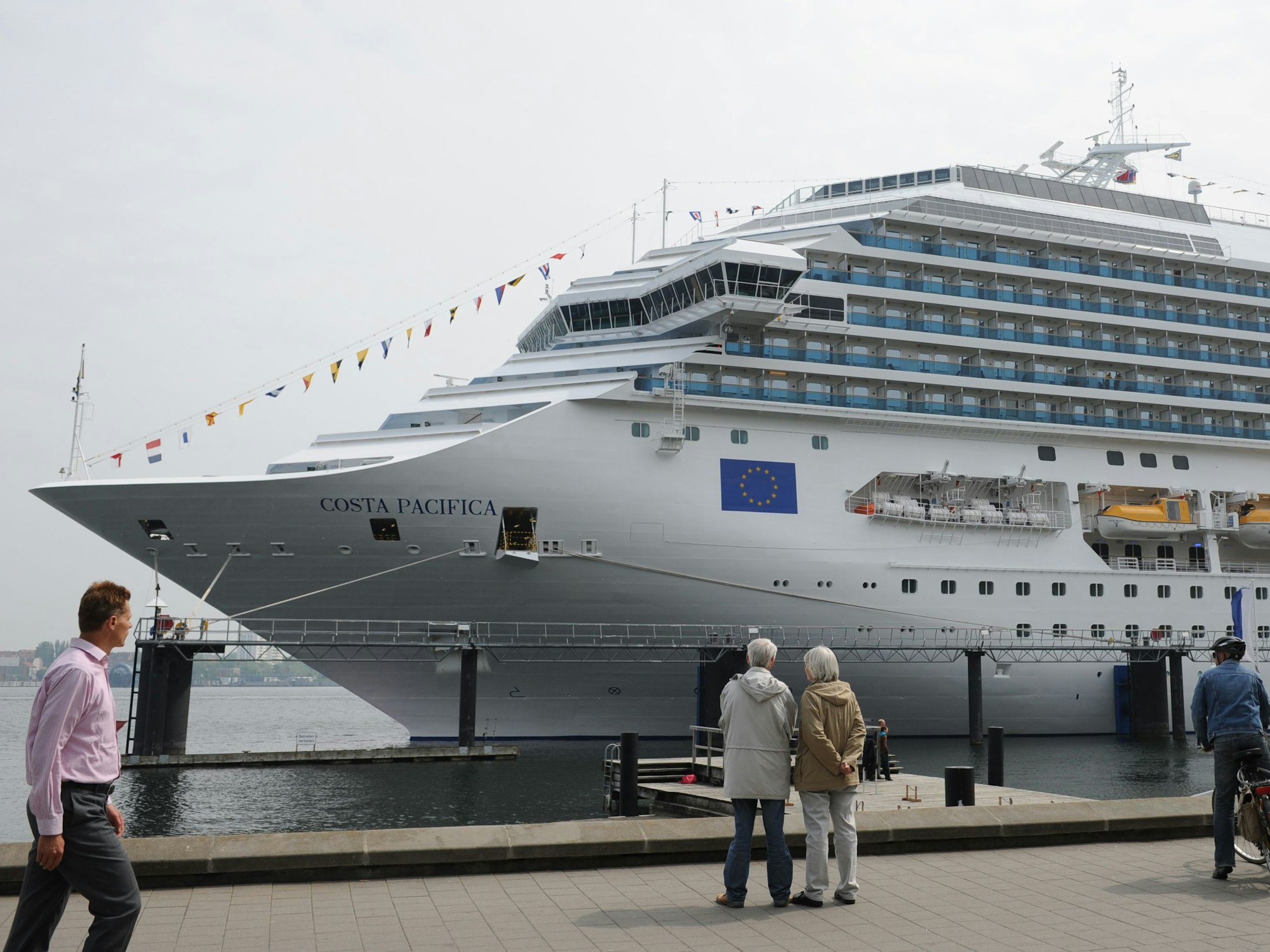 Passanten und Passantinnen betrachten in Kiel im Hafen die 290 Meter lange Costa Pacifica