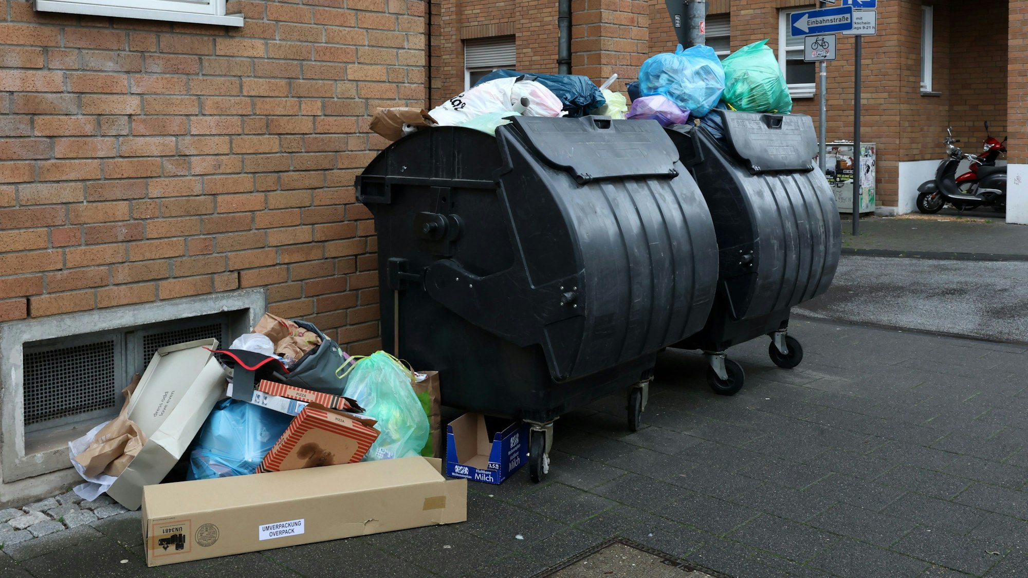 Volle Mülltonnen stehen vor einem Wohnhaus in Köln.
