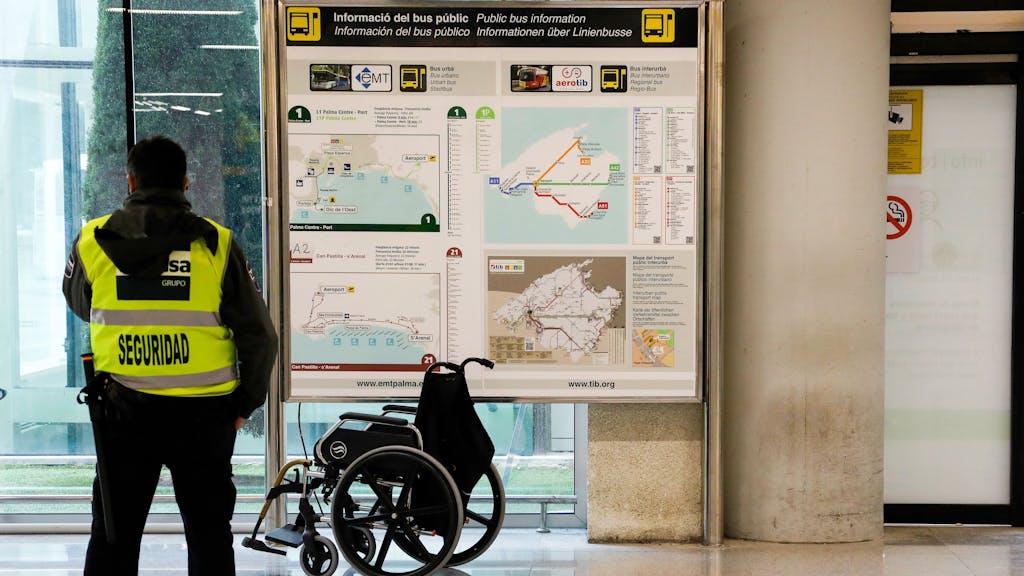 Ein Sicherheitsmann steht am Flughafen von Palma de Mallorca vor einem Rollstuhl