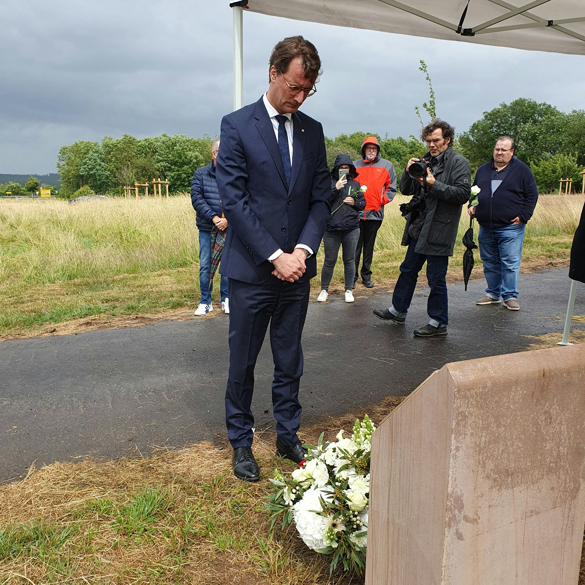 Ministerpräsident Hendrik Wüst steht andächtig vor dem Denkmal der Flutopfer.