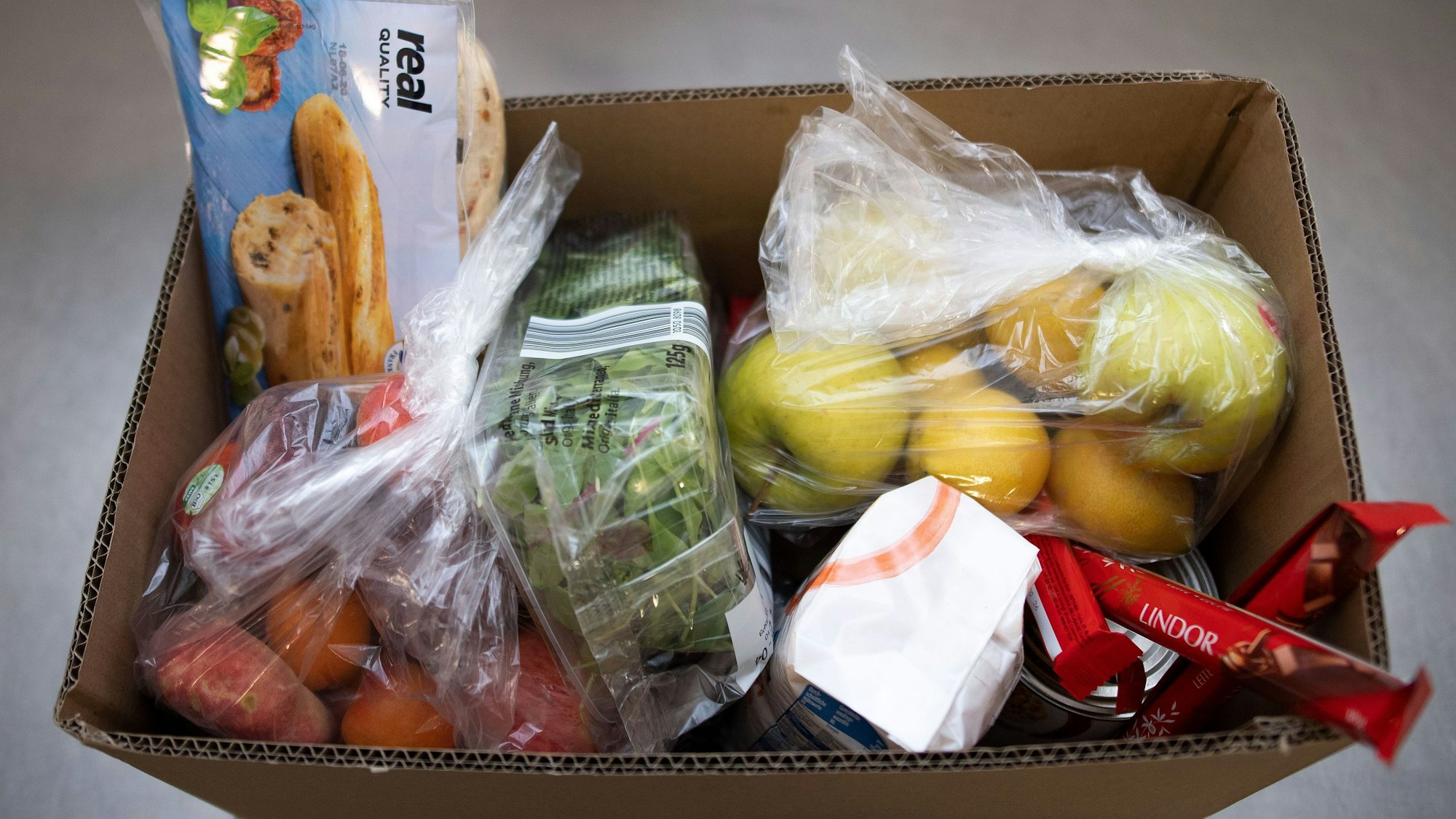 Ein Karton mit Lebensmitteln steht in den Räumen der Aachener Tafel.