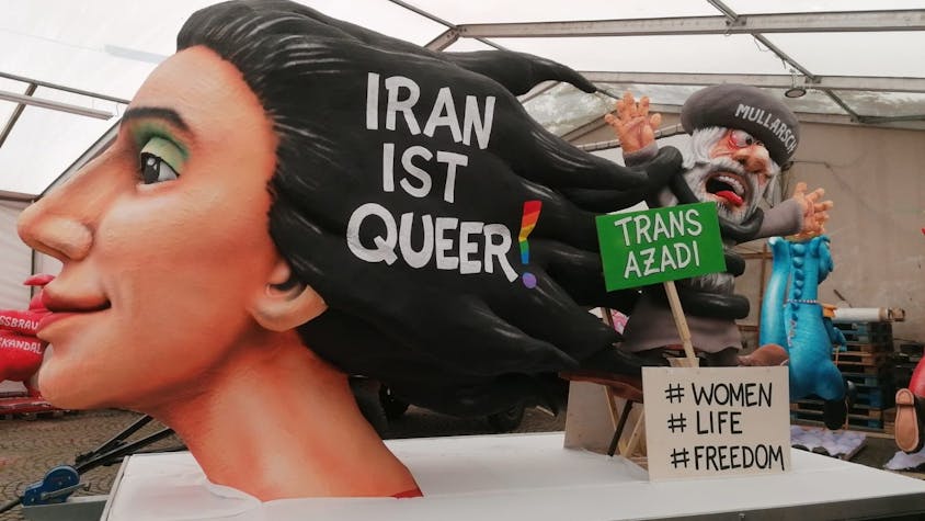 Der Woman-Life-Freedom-Wagen auf dem Kölner CSD wurde von Jaques Tilly gebaut. Vorne wird ein Kunstwerk einer Frau sein, die mit ihren Haaren einen Mullah erwürgt. Zusätzlich steht "Iran ist queer!" in ihren Haaren. Auf einem grünen Schild steht außerdme „Trans Azadi“, auf einem weiteren „#Women #Life #Freedom“.