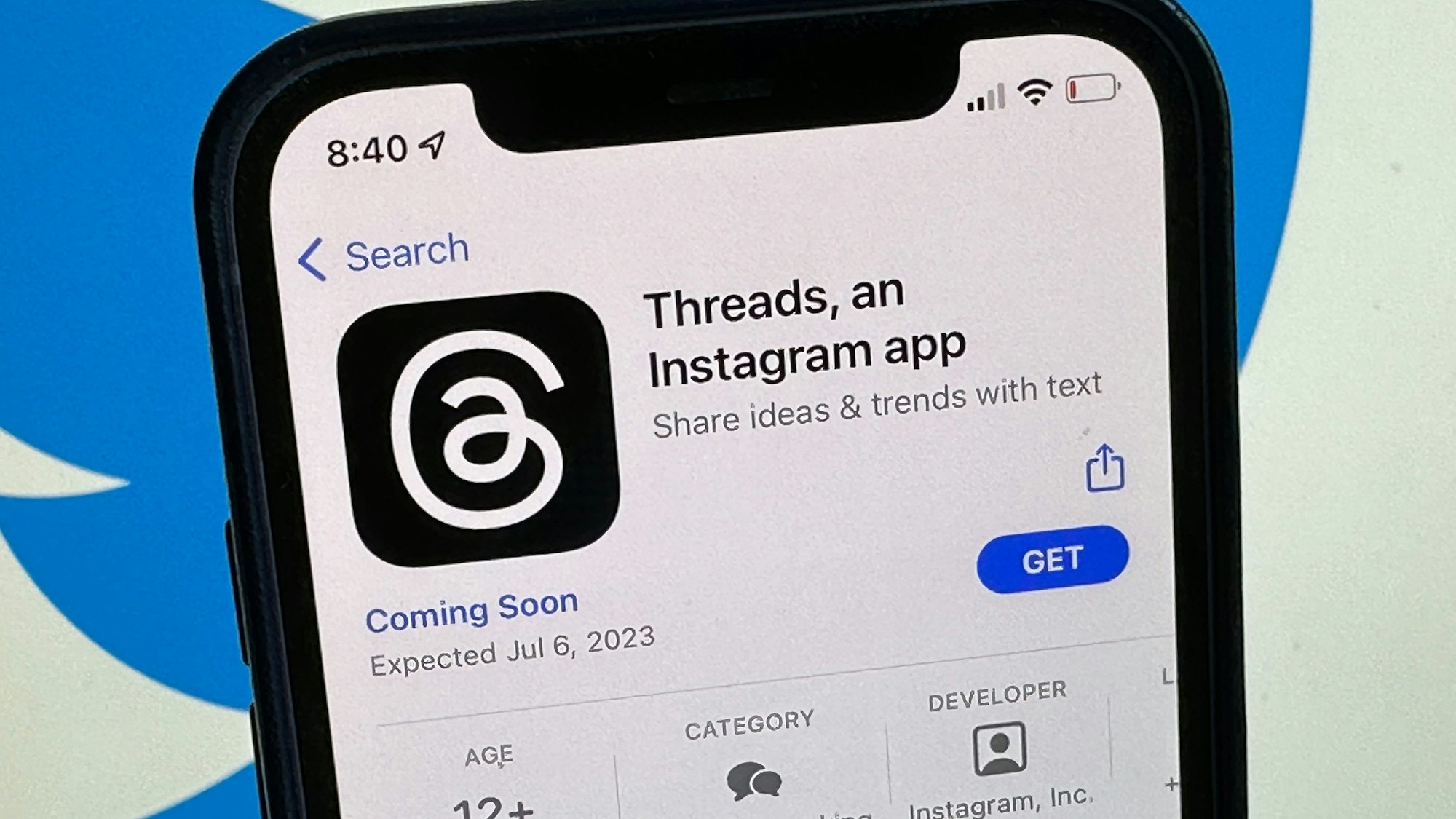 Die Ankündigung der Social-Media-App Threads wird im US-amerikanischen App Store von Apple angezeigt. Im Hintergrund ist das Twitter-Logo zu sehen.