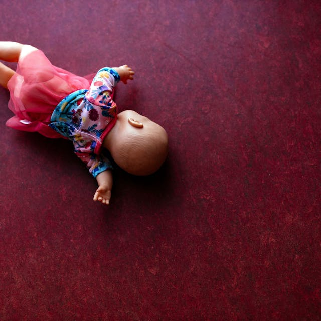 Eine Spielzeugpuppe liegt auf einem PVC-Fußboden.&nbsp;