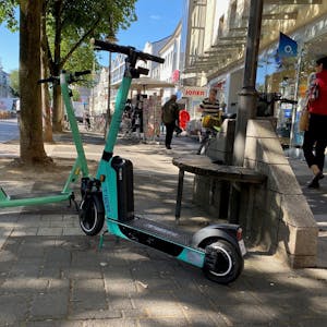 Zwei E-Scooter stehen in der Brühler Fußgängerzone, Passanten umkurven die kleinen Elektroflitzer.