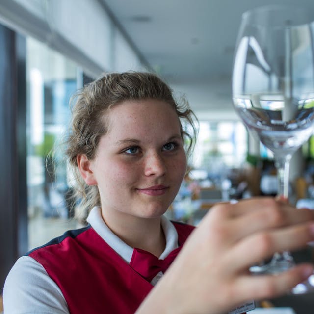 Alles muss blitzen: Eine Jugendliche kontrolliert in einem Restaurant ein frisch geputztes Weinglas. Auch Oberbergs Gastronomie wartet mit einem vielseitigen Angebot an Ferienjobs auf.