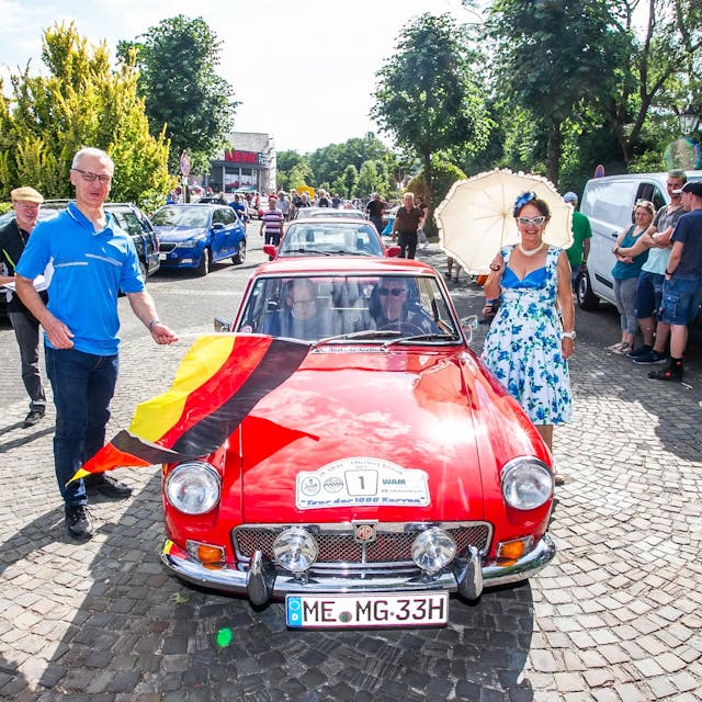 Lindlars Bürgermeister schwenkt die Startflagge bei der Abfahrt zur ADAC-Oldtimer-Rallye.