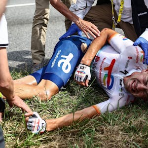 Steff Cras (M) aus Belgien vom Team TotalEnergies reagiert nach seinem Sturz auf der Strecke mit schmerzverzerrtem Gesicht