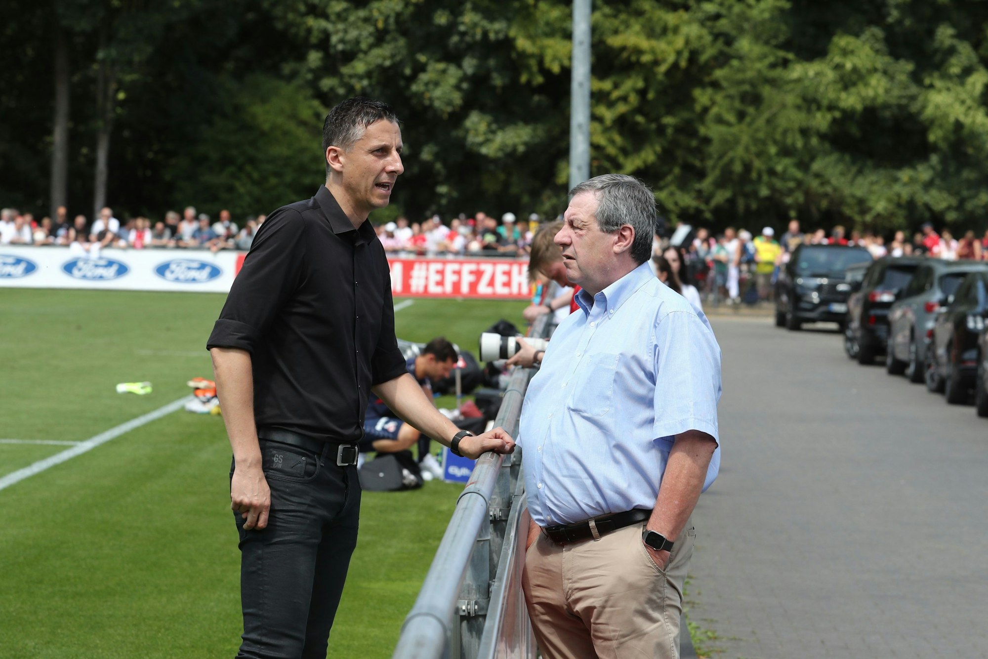 Sport-Geschäftsführer Christian Keller (l.) und Präsident Werner Wolf unterhalten sich während des Trainingsauftakts des 1. FC Köln am Montag.