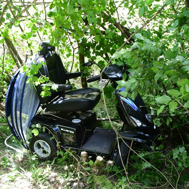 Das Bild zeigt einen Elektro-Scooter, der bei einem Unfall in dichtem Gestrüpp gelandet ist.