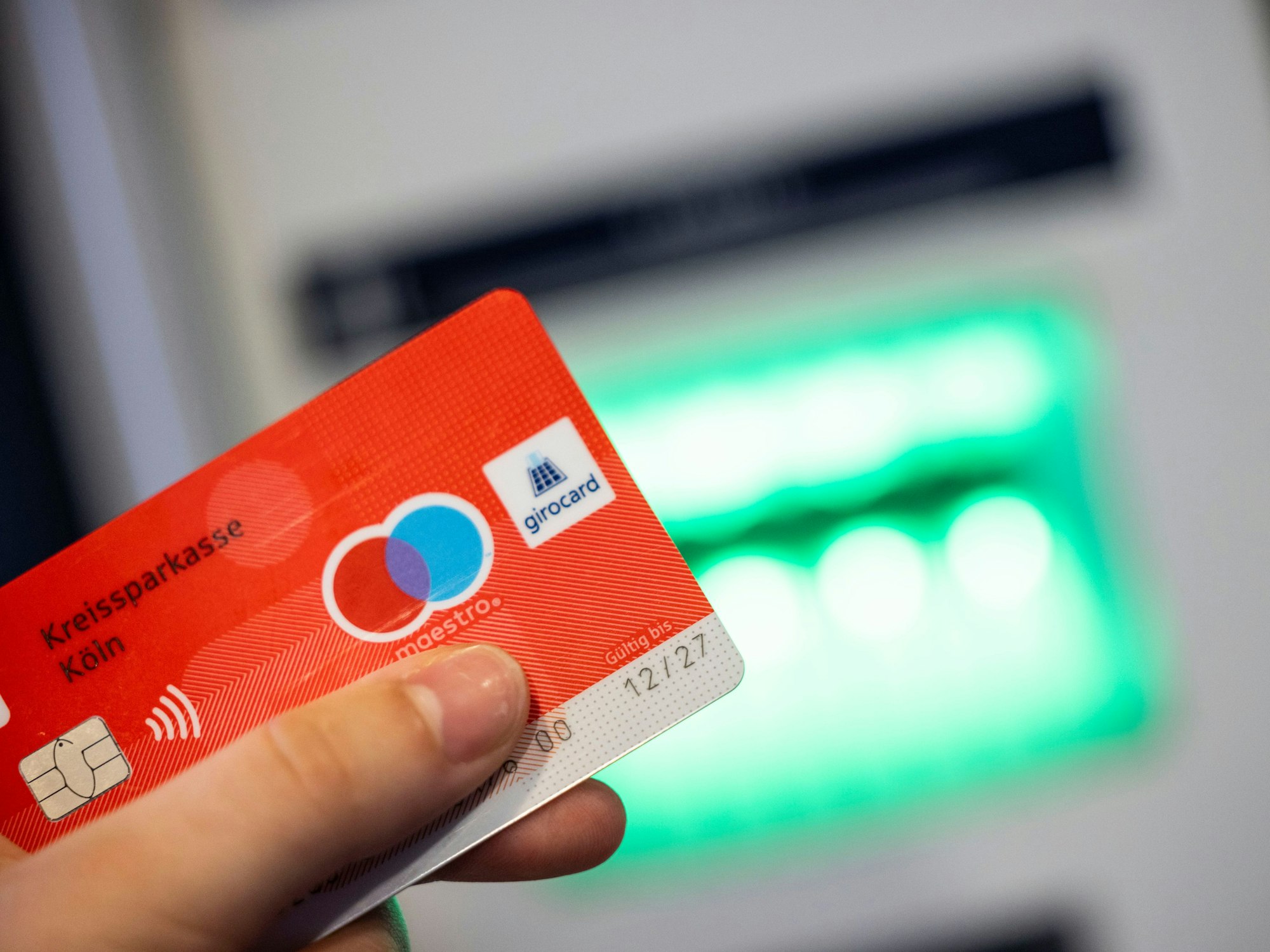 Eine Bankkundin verwendet ihre Girokarte, auf der das Girocard-Logo und das rot-blaue Maestro-Logo abgebildet sind, um Bargeld an einem Geldautomaten abzuheben, hier im Juni 2023.