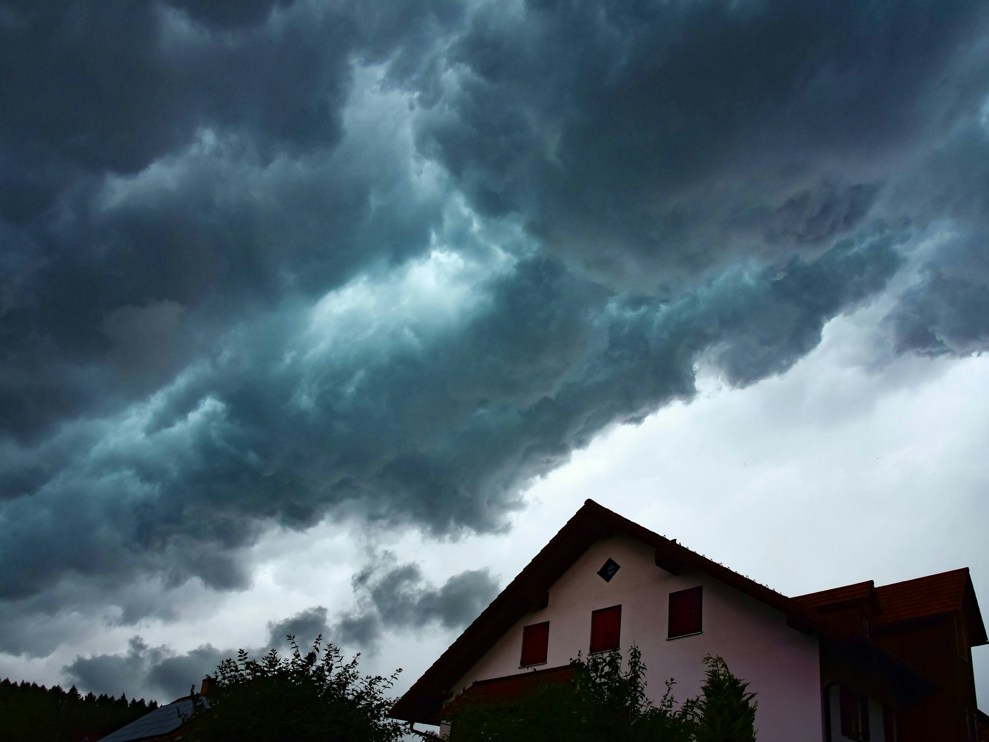 Gewitterwolken über einem Wohnhaus in Bayern, Deutschland.
