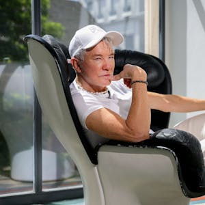 10.07.2023, Köln: Hollywood-Regisseur Baz Luhrmann sitzt in einem Drehsessel im Kölner Qvest-Hotel.

Er trägt eine weiße Baseball-Kappe, ein weißes T-Short und weiße Jeans.