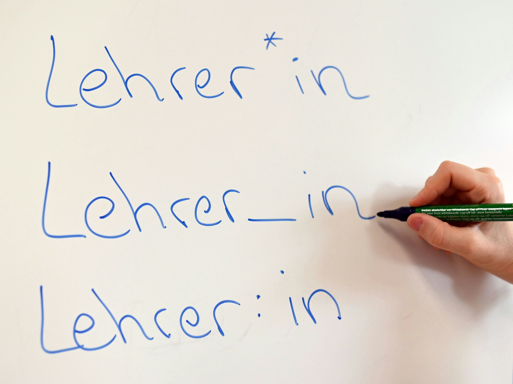 An einem Whiteboard steht das Wort „Lehrer“ in drei verschiedenen Gender-Schreibweisen.