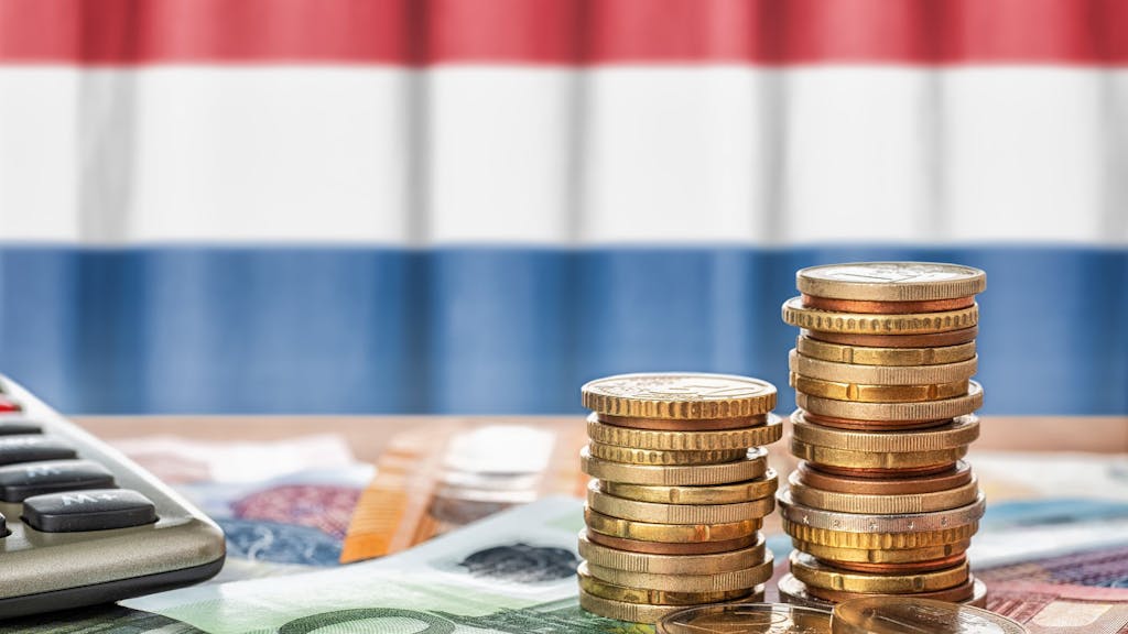 Euro Banknoten und Münzen liegen vor der niederländischen Flagge.