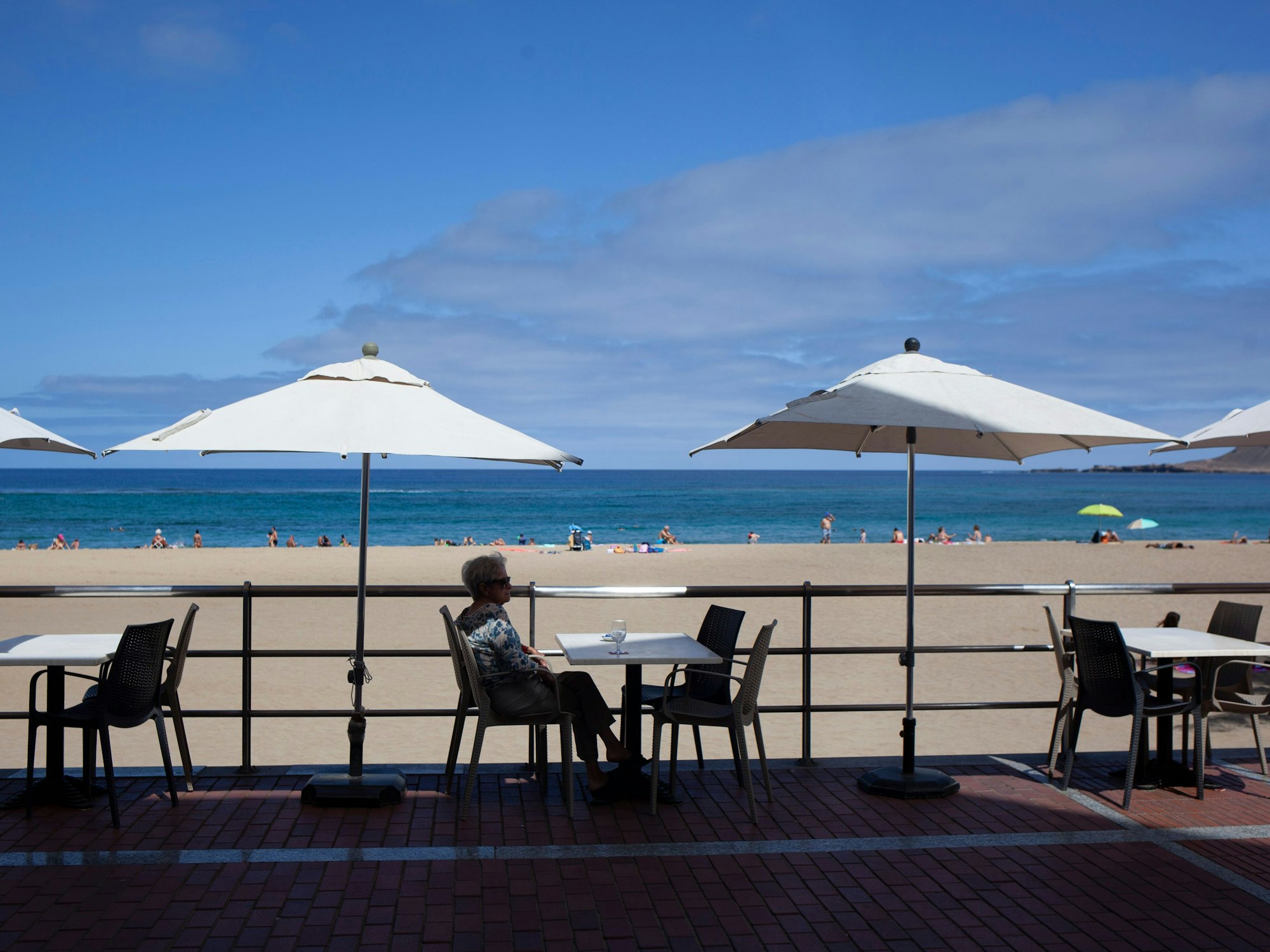Eine Frau nimmt ein Getränk auf der Terrasse einer Bar am Strand in Las Palmas de Gran Canaria zu sich.