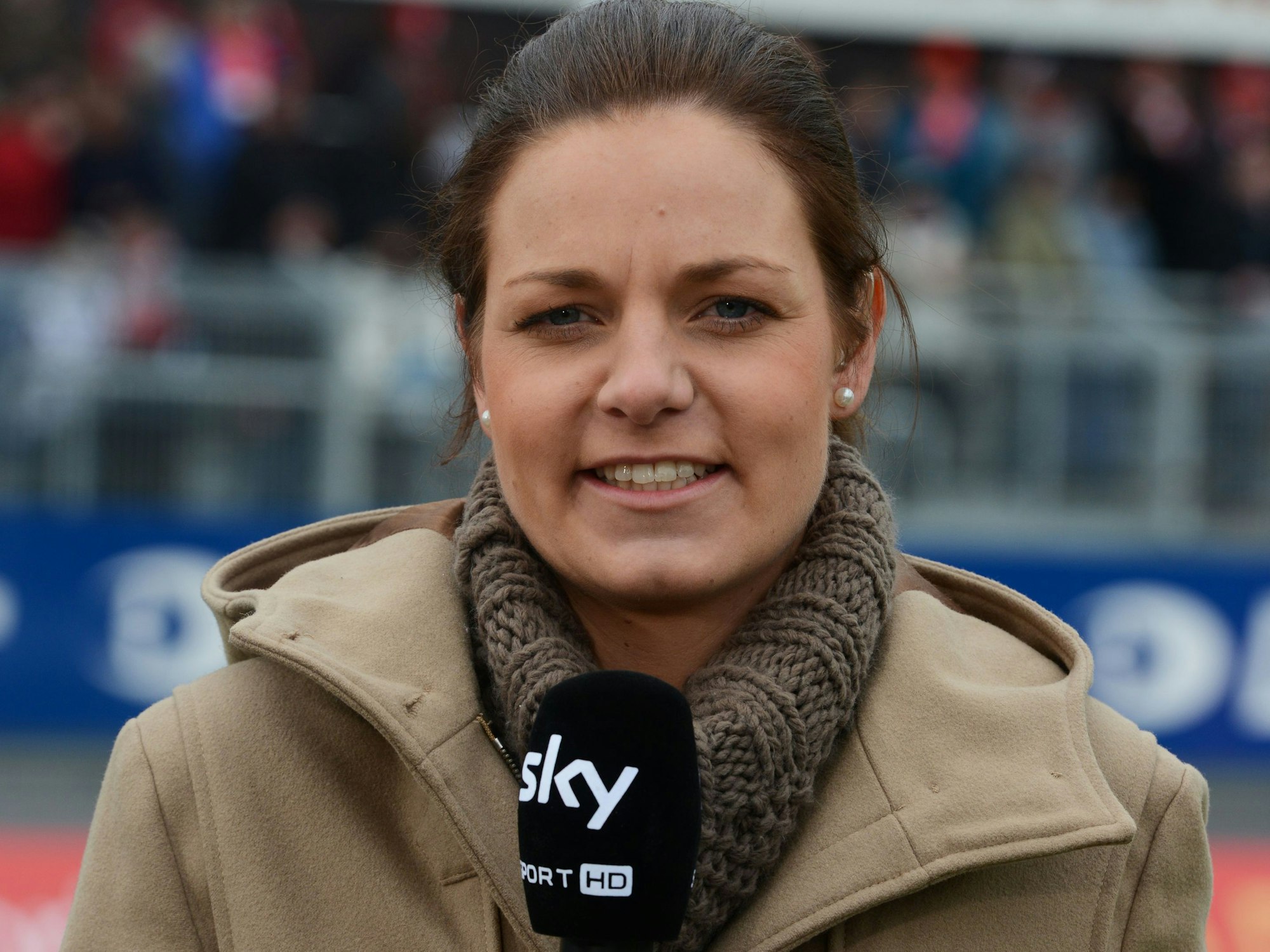 Christina Graf steht mit einem Mikrofon von Sky im Stadion.