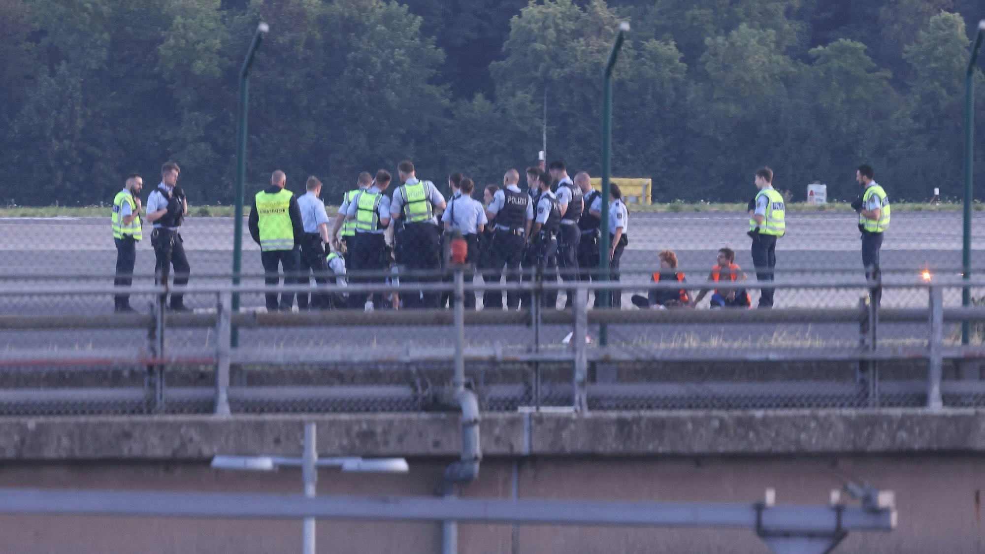 Düsseldorfer Flughafen am Donnerstagmorgen: Mehrere Mitglieder der Letzten Generation haben ein Rollfeld des Airports blockiert, Polizistinnen und Polizisten sind im Einsatz.