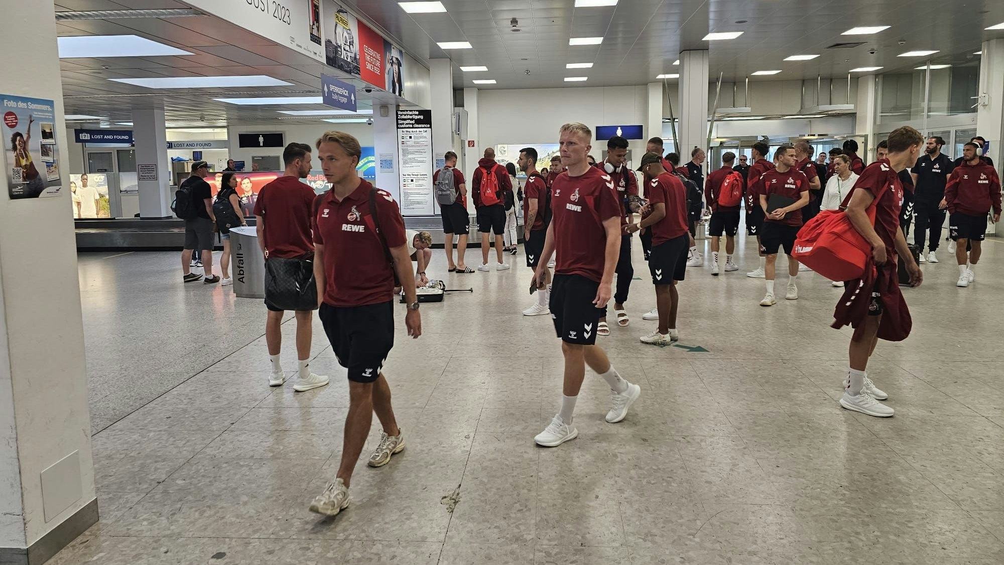 Die Mannschaft des 1. FC Köln wartet am Flughafen auf ihre Koffer.