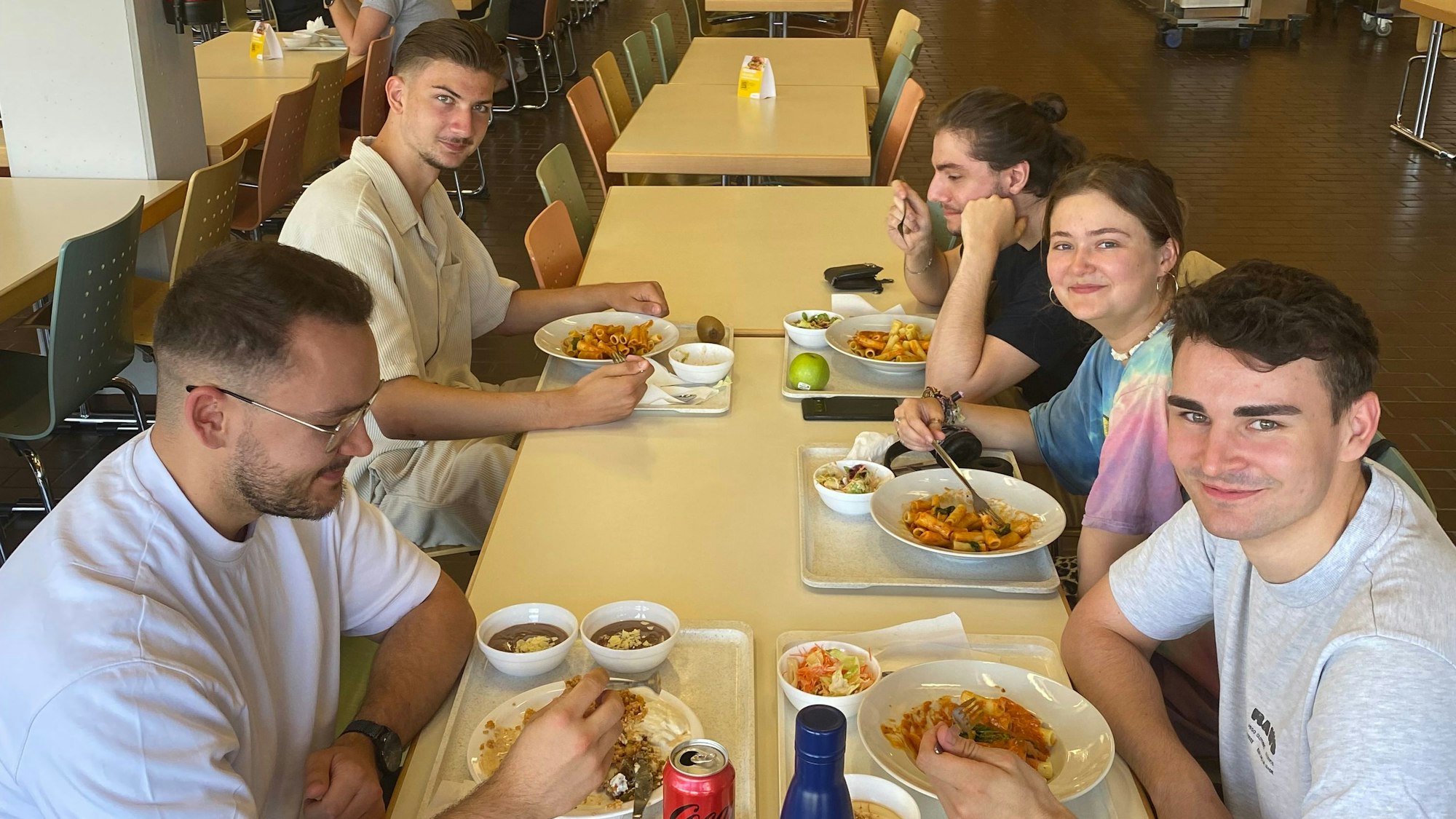 Auf dem Bild sieht man fünf junge Erwachsene beim Essen.