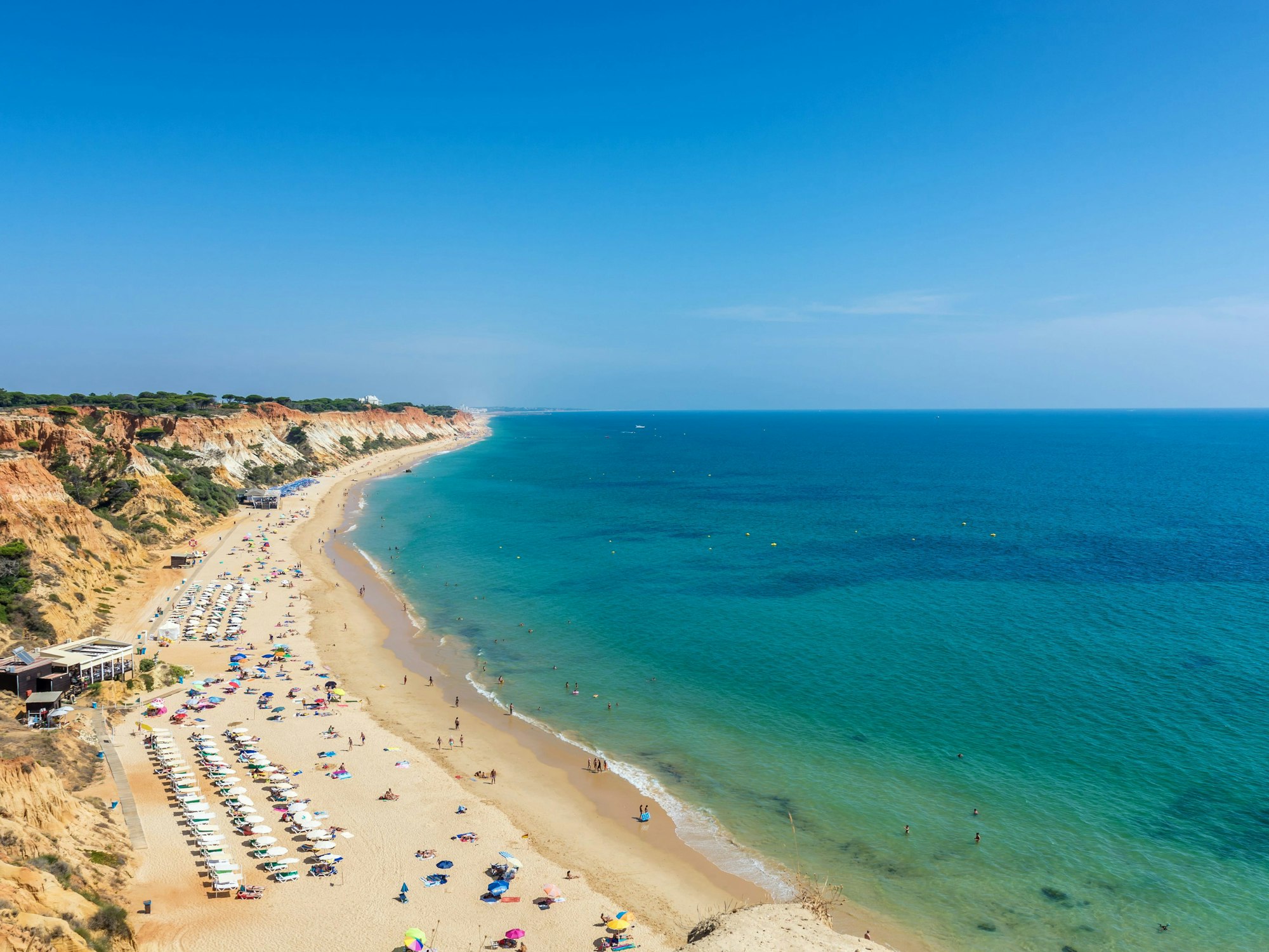 Sonnenliegen und Badegäste an der Praia da Falésia in Albufeira (Portugal). Der Strand zählt zu den besten preiswerten Stränden in Europa.