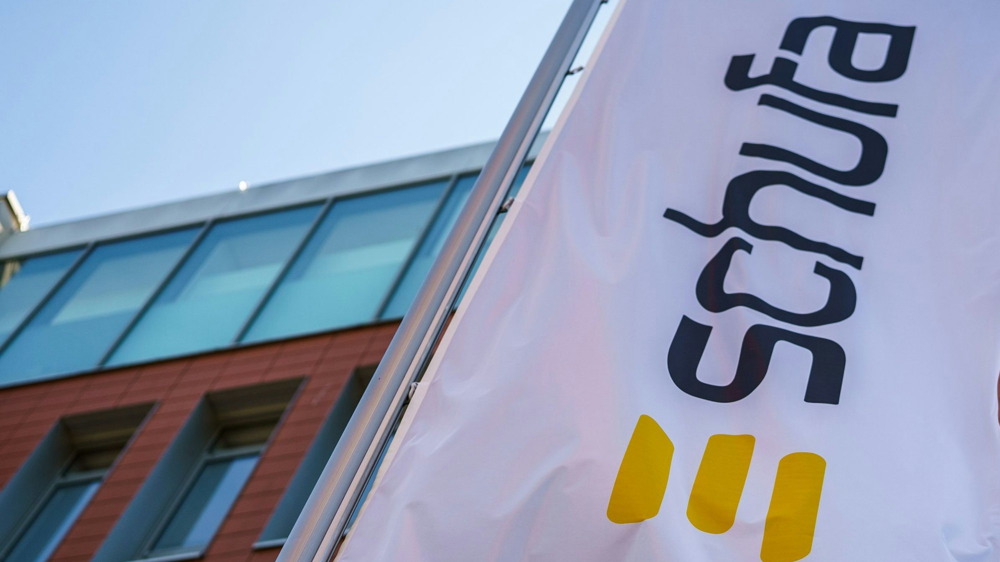 Eine Flagge mit dem Firmenlogo der Schufa, drei breiten gelben Querstreifen, flattert vor dem Geschäftssitz in Wiesbaden.