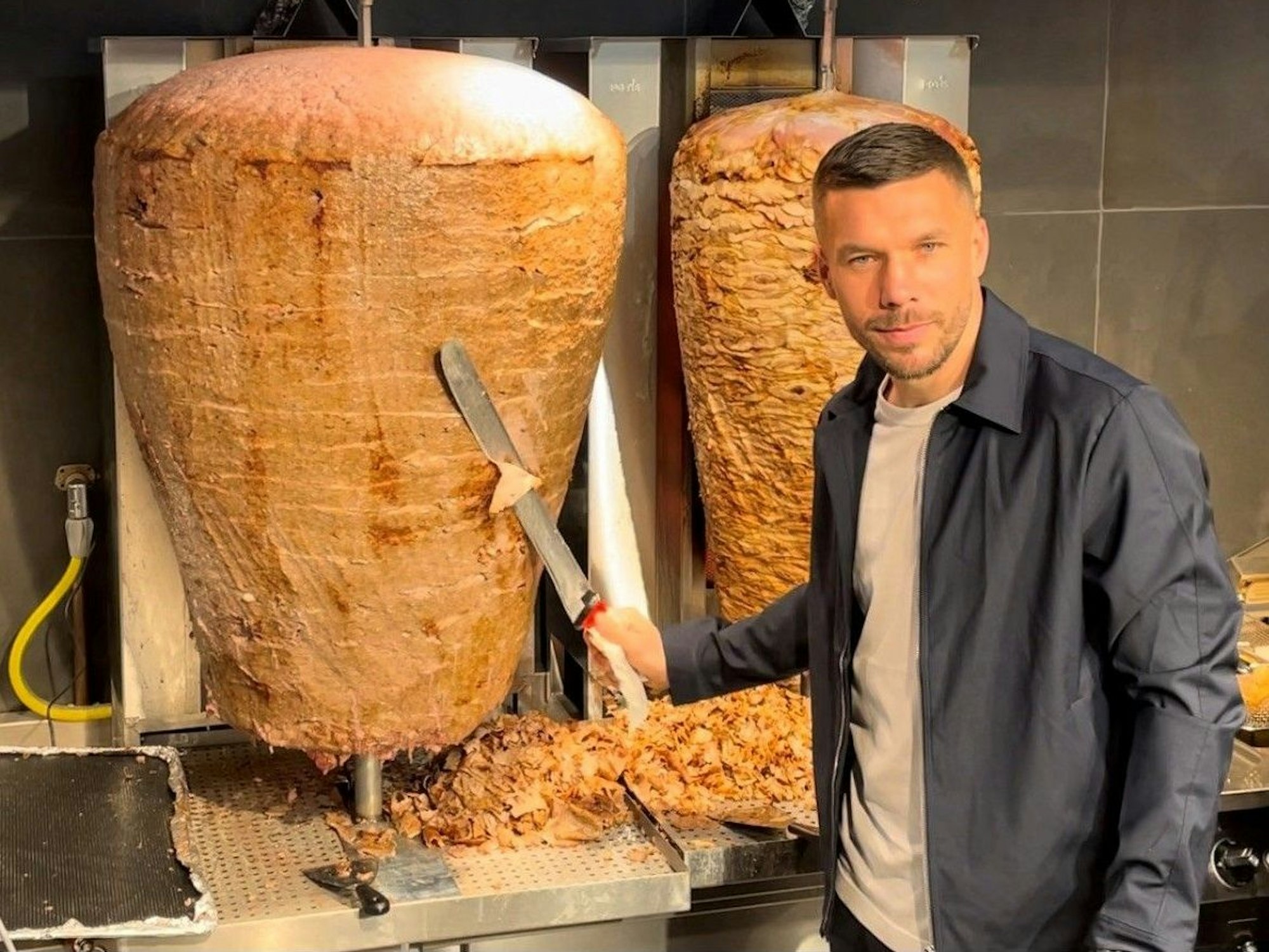 Lukas Podolski steht am Dönerspieß.