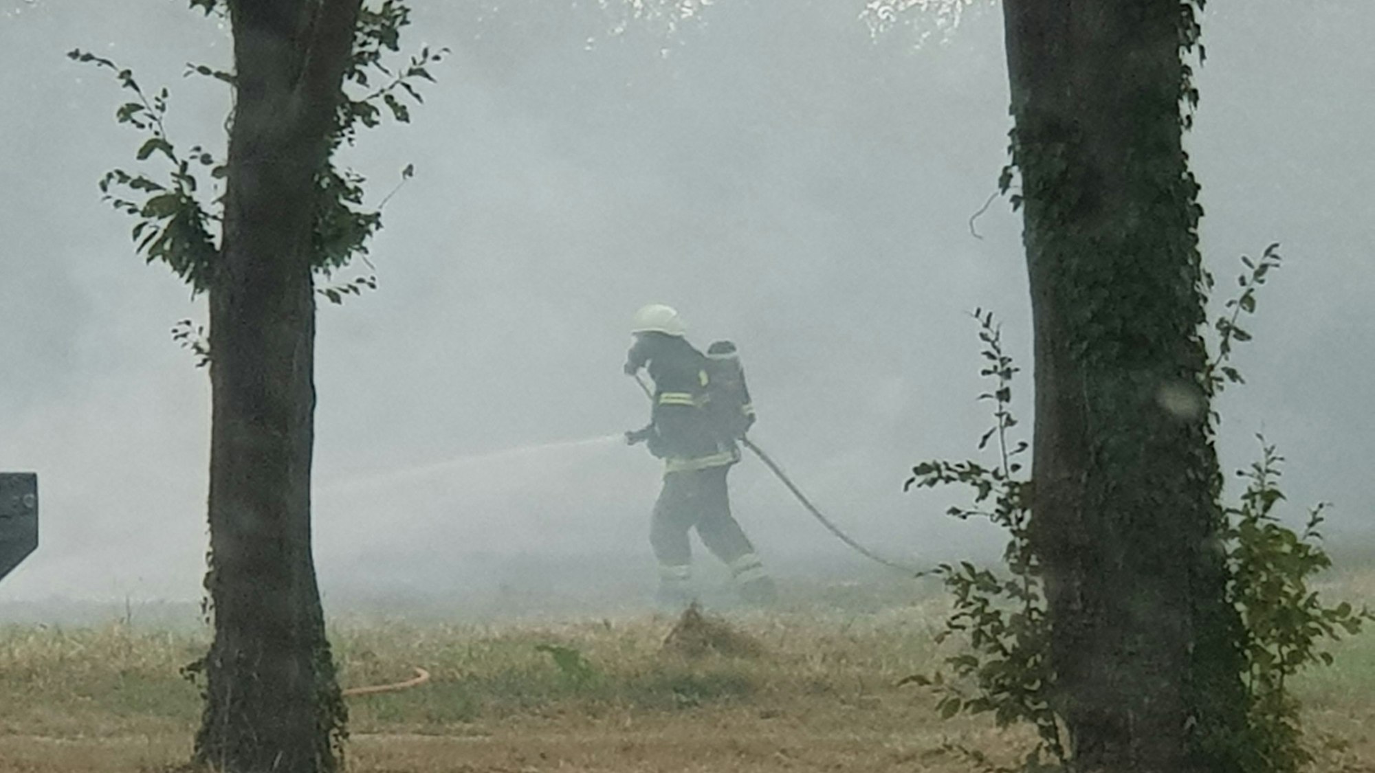 Das Bild zeigt einen Feuerwehrmann mit Atemschutzmaske auf einem Feld.