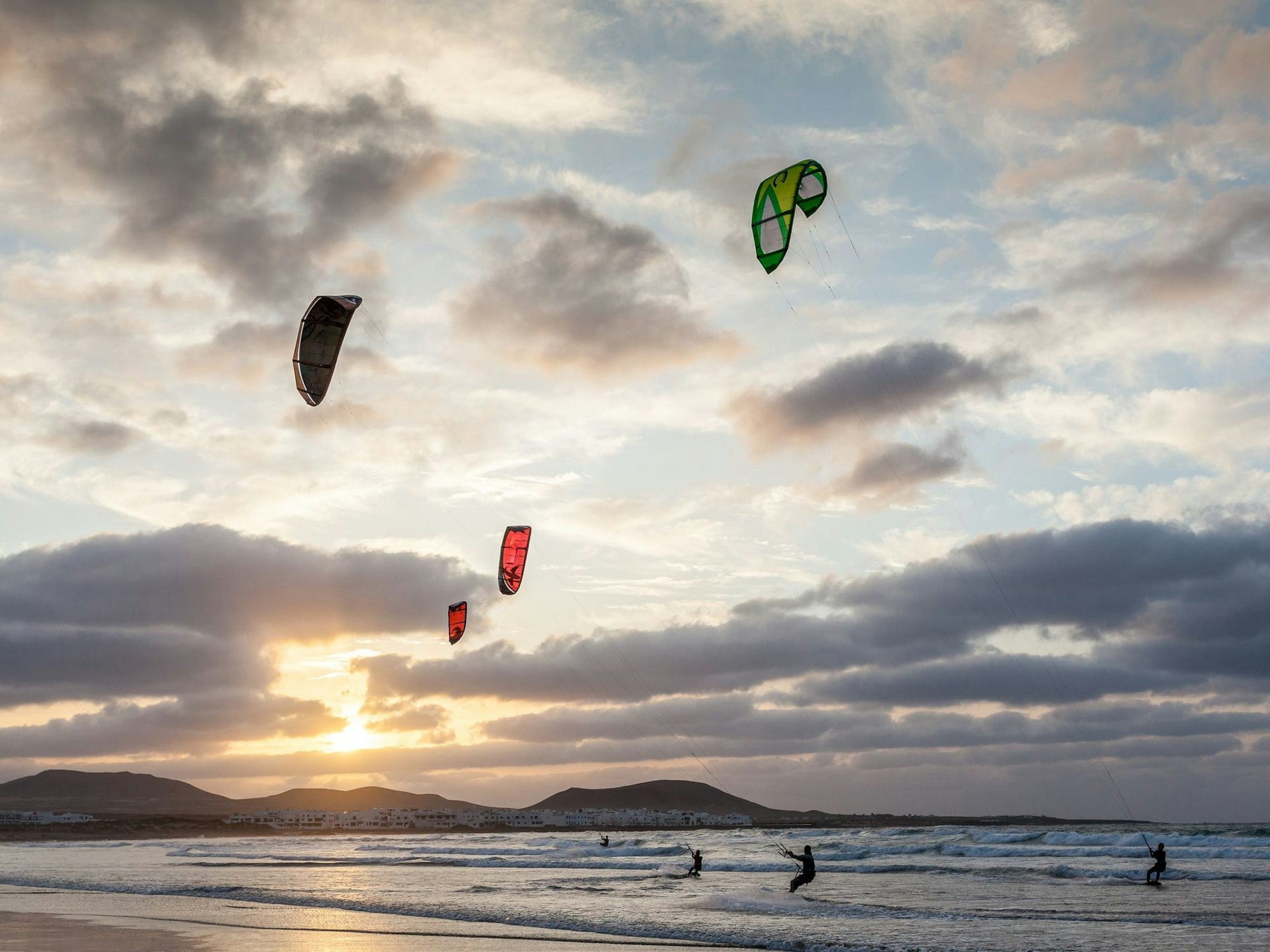 Kitesurfer surfen bei Sonnenuntergang auf dem Meer.
