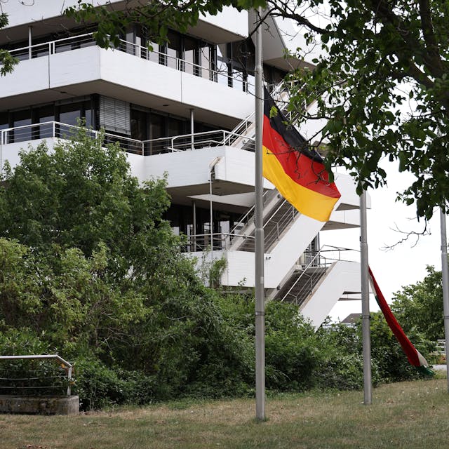 Eine Deutschlandflagge weht an einem Fahnenmast, im Hintergrund ist das Euskirchener Kreishaus zu sehen.