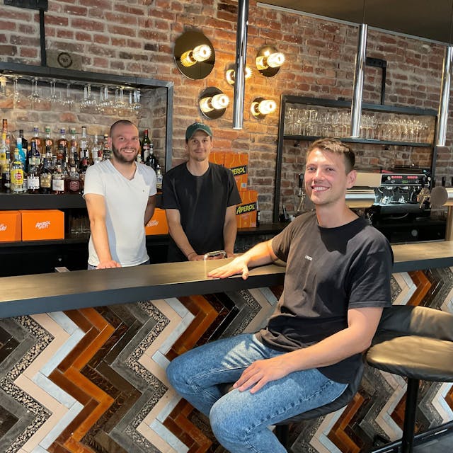 Drei junge Männer an einer Bar