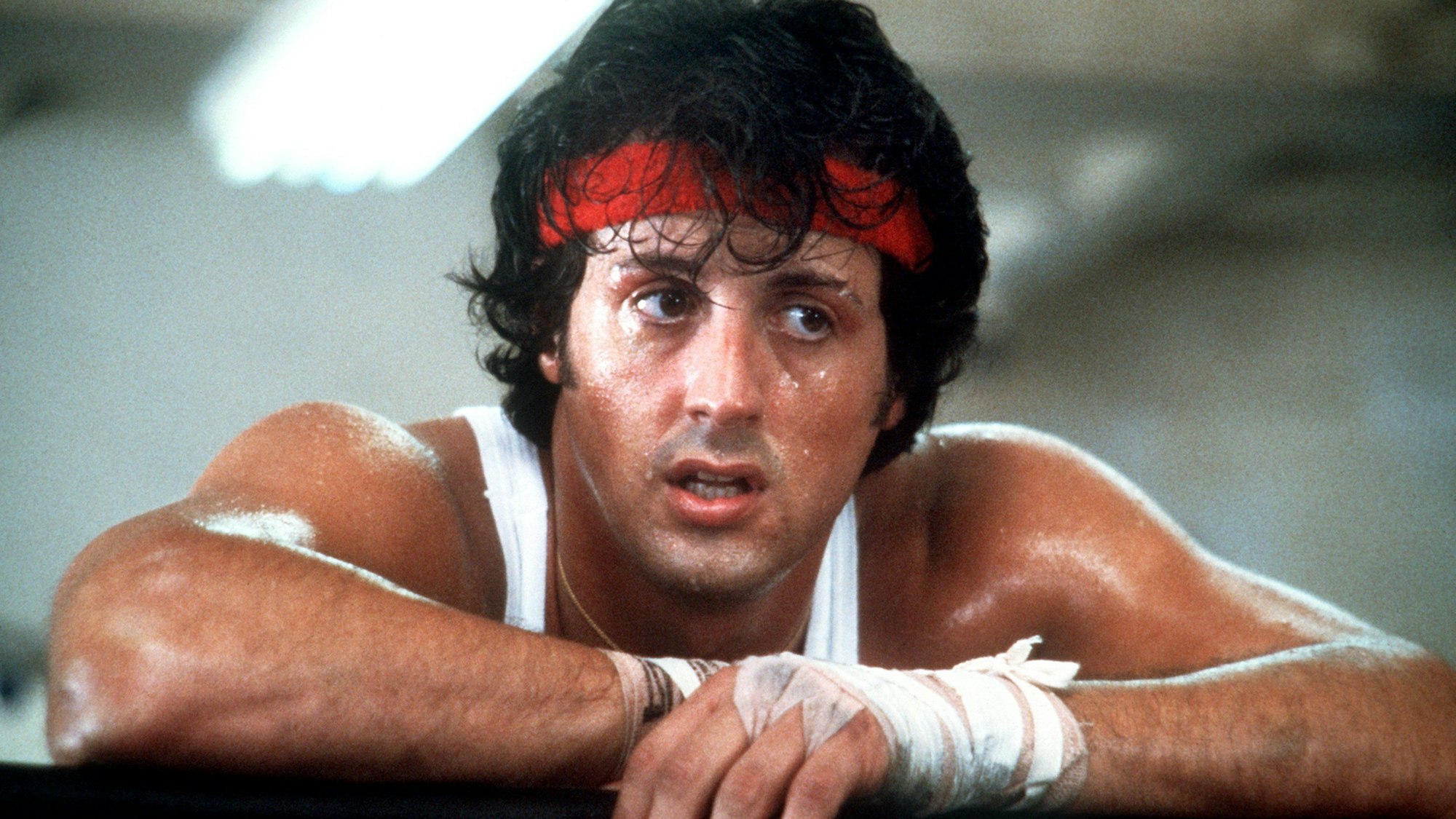 Erschöpft hängt der US-amerikanische Schauspieler Sylvester Stallone in den Seilen während den Dreharbeiten zu dem Boxer-Film „Rocky II“.