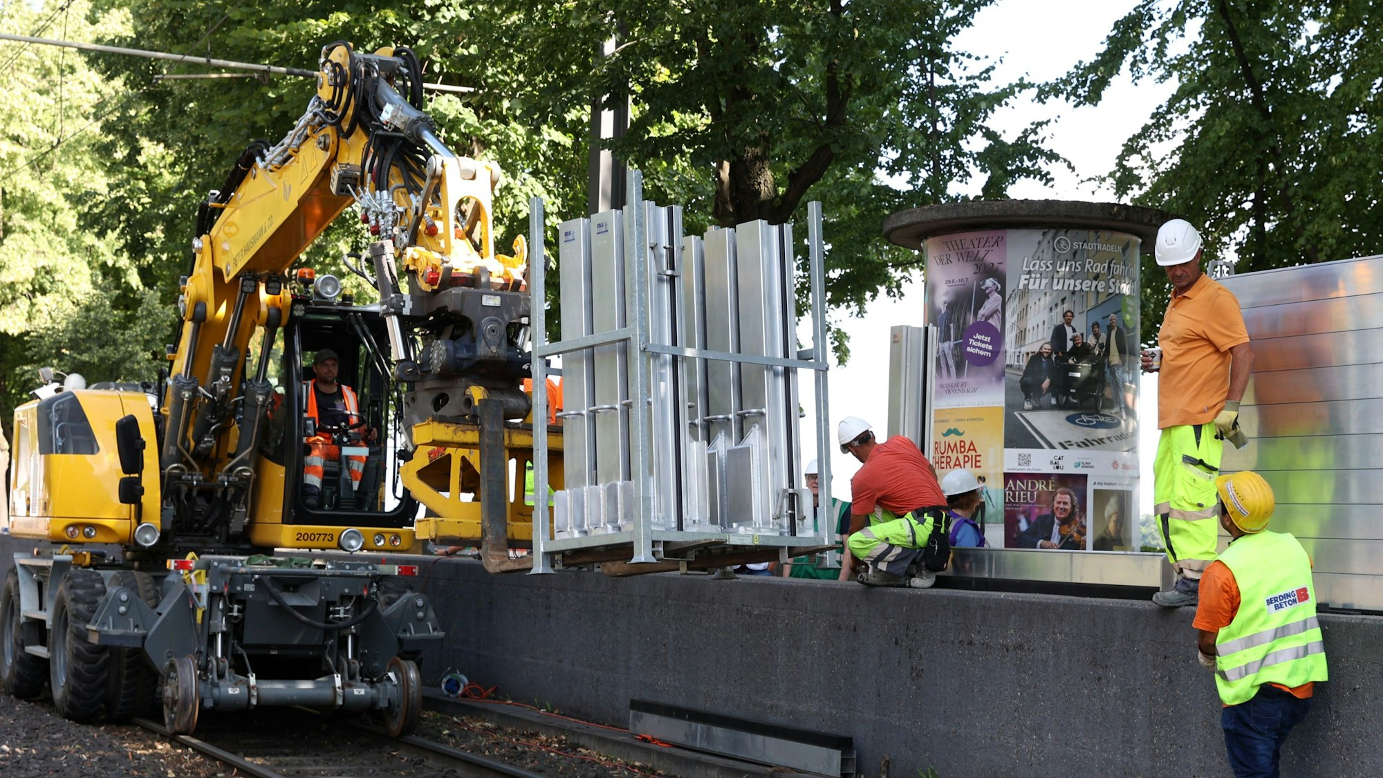 Personen bauen eine mobile Wand auf, die über ein Schienenfahrzeug angeliefert wird.