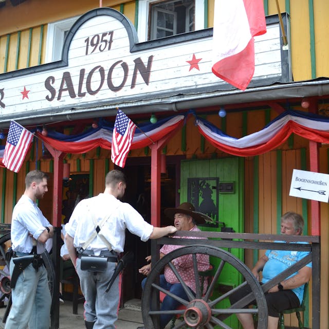 Männer stehen vor einem Wildwest-Saloon.