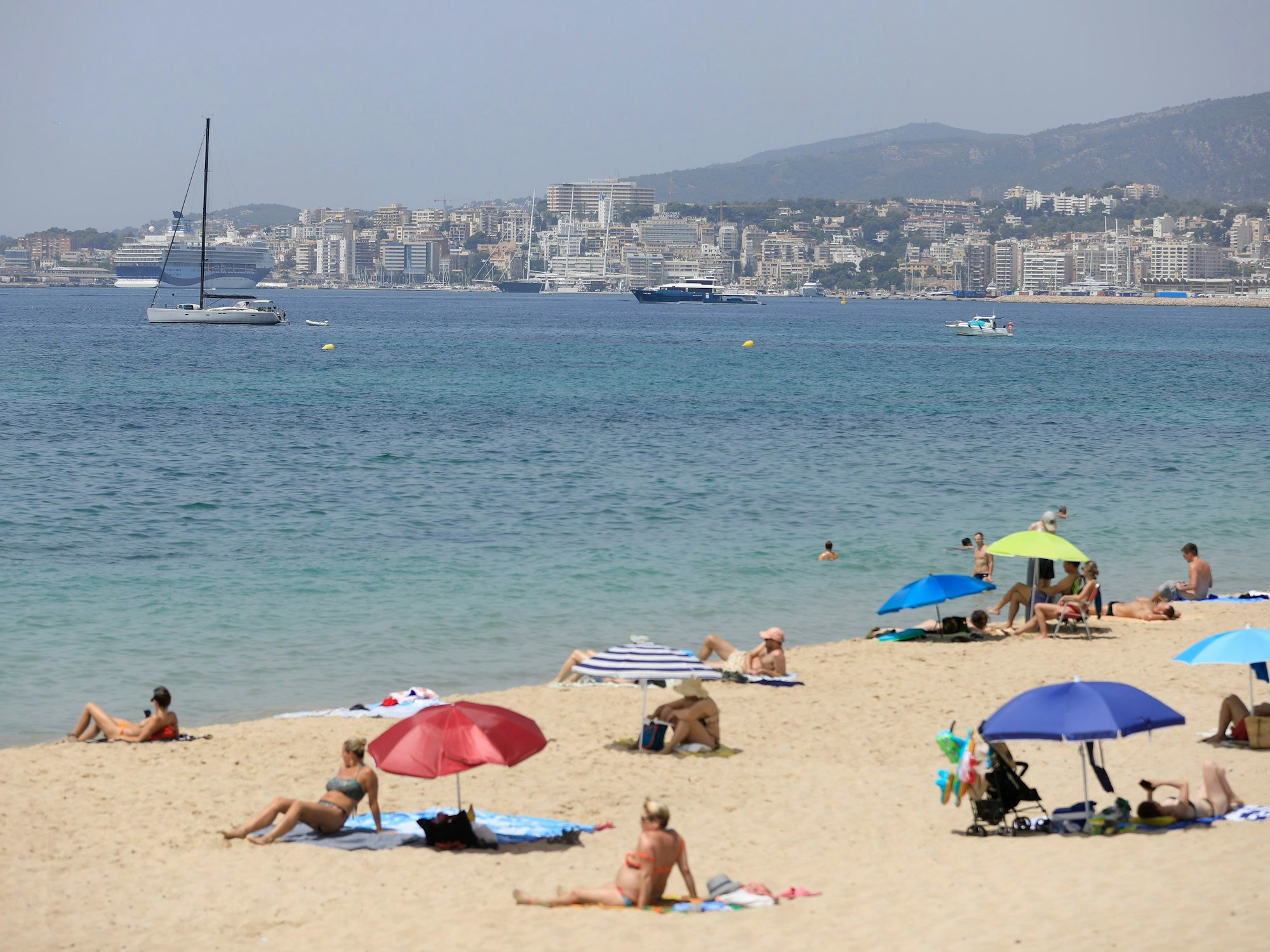 Menschen sonnen sich und benutzen Sonnenschirme am Strand.