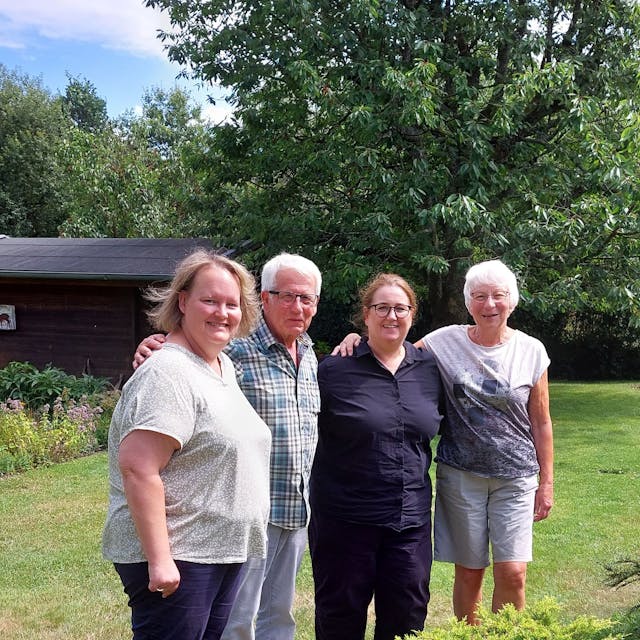 Vier Personen stehen in einem Garten und betrachten den Wiederaufbau nach der Flutkatastrophe 2021.