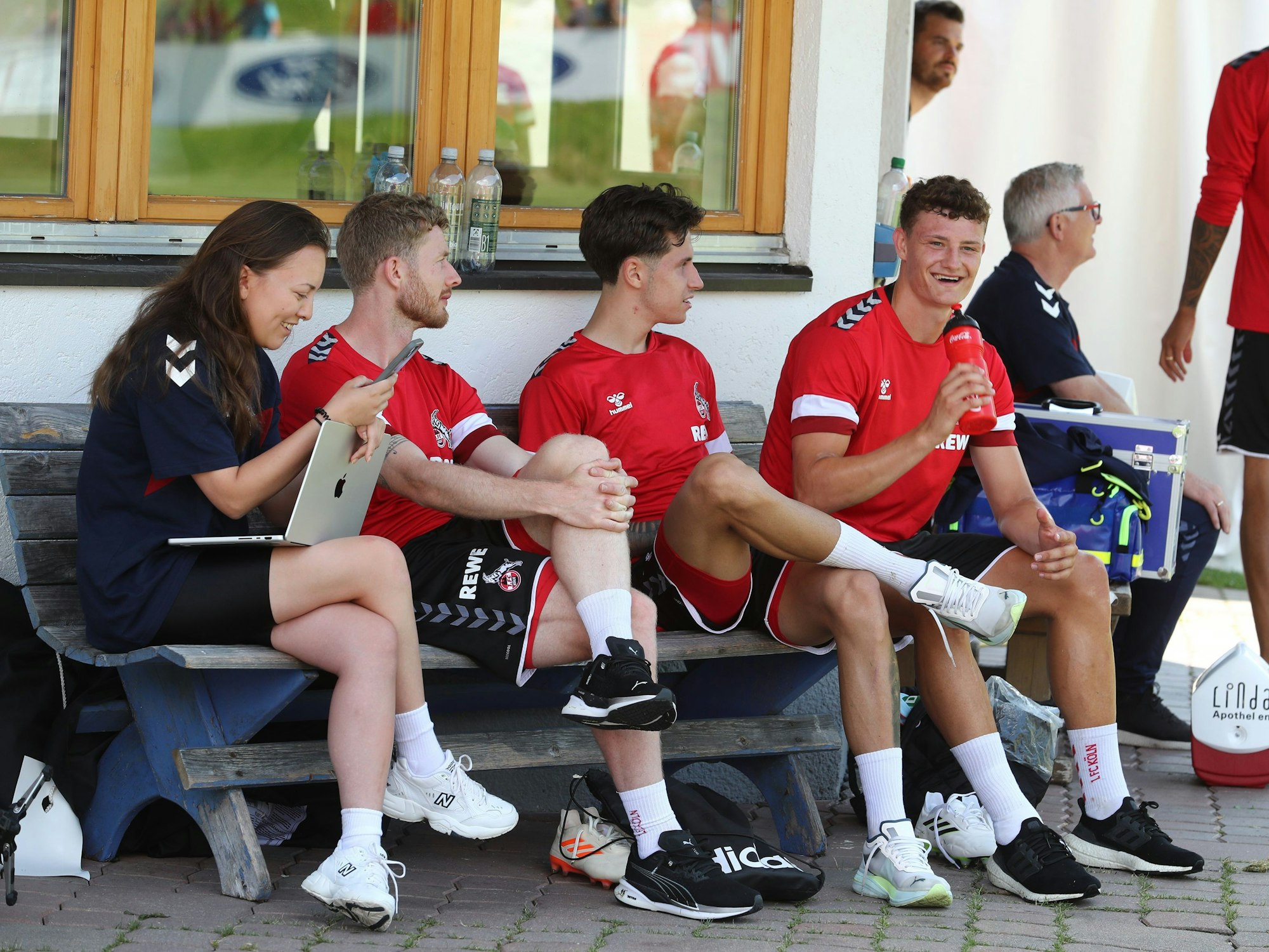 Die FC-Profis Eric Martel, Denis Huseinbasic und Florian Kainz (v.r.n.l.) unterhielten sich nach dem Training am Montag (17. Juli 2023) auf einer Bank.