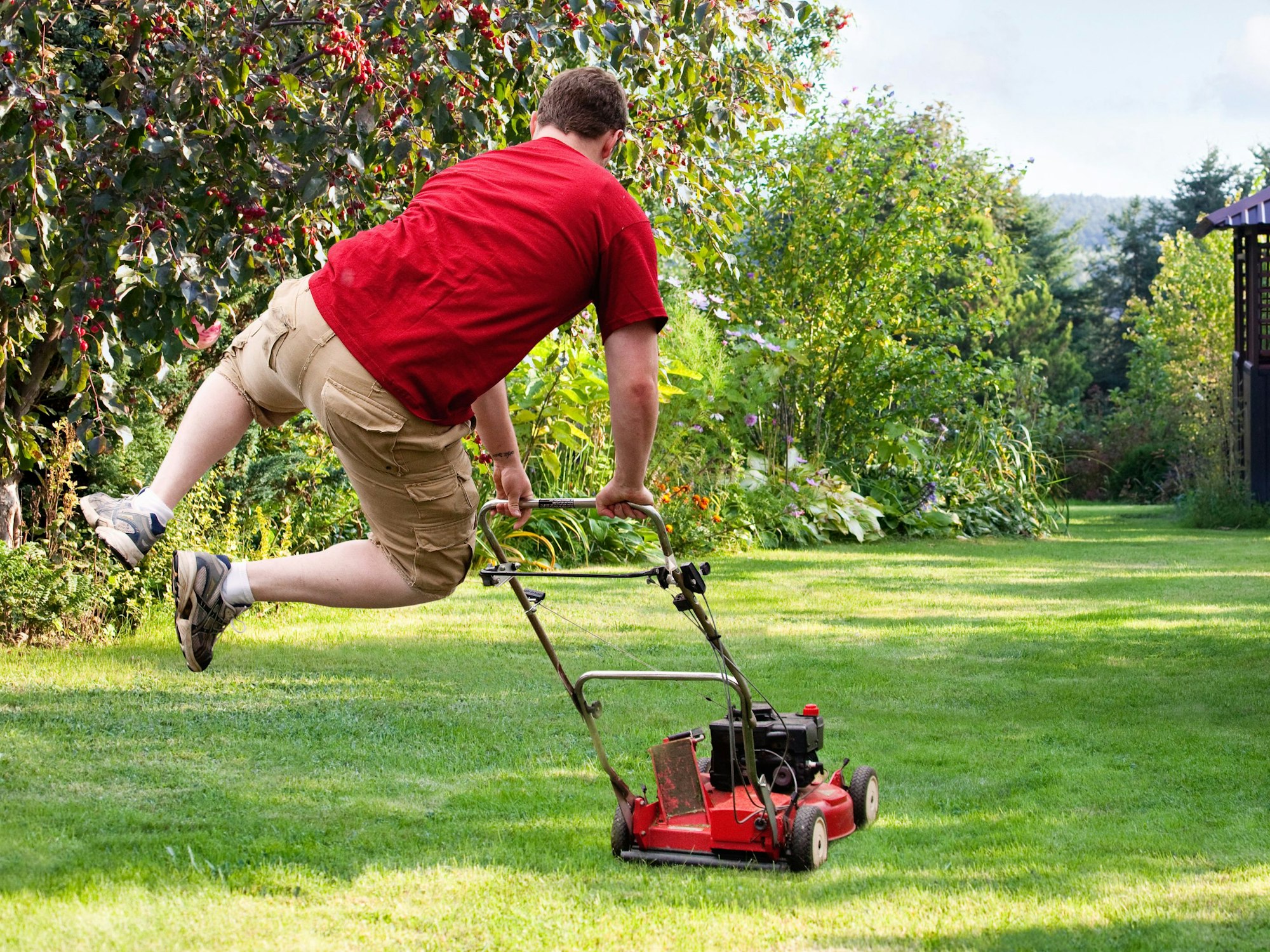 Mann hüpft beim Rasenmähen vor Freude in die Luft